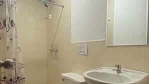 A bathroom with a toilet, a shower, a sink, and a mirror. - Hospedaje La Pascana (Cajamarca)