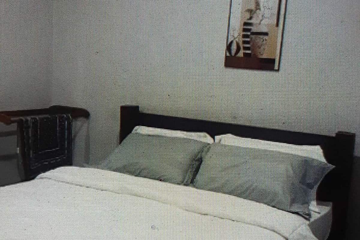A bed with a wooden headboard, a pillow, and a wall-mounted picture frame.