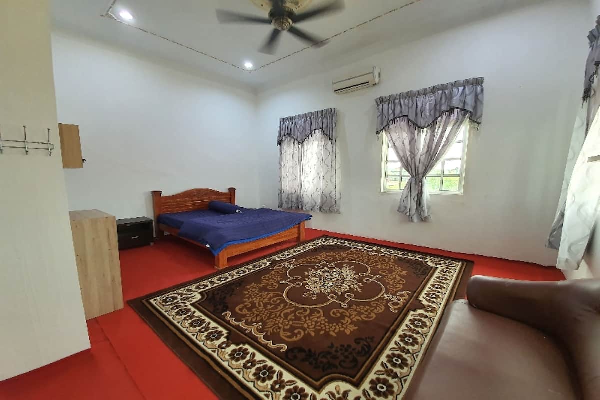 A bedroom with a bed, a ceiling fan, a window with curtains, and a red carpet.