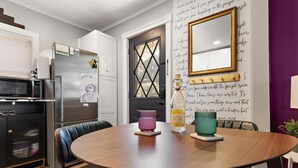 A modern kitchen with a refrigerator, microwave, and a dining table with chairs.