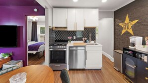 A compact kitchen with white cabinets, a black tiled backsplash, and a star-shaped sign on the wall.