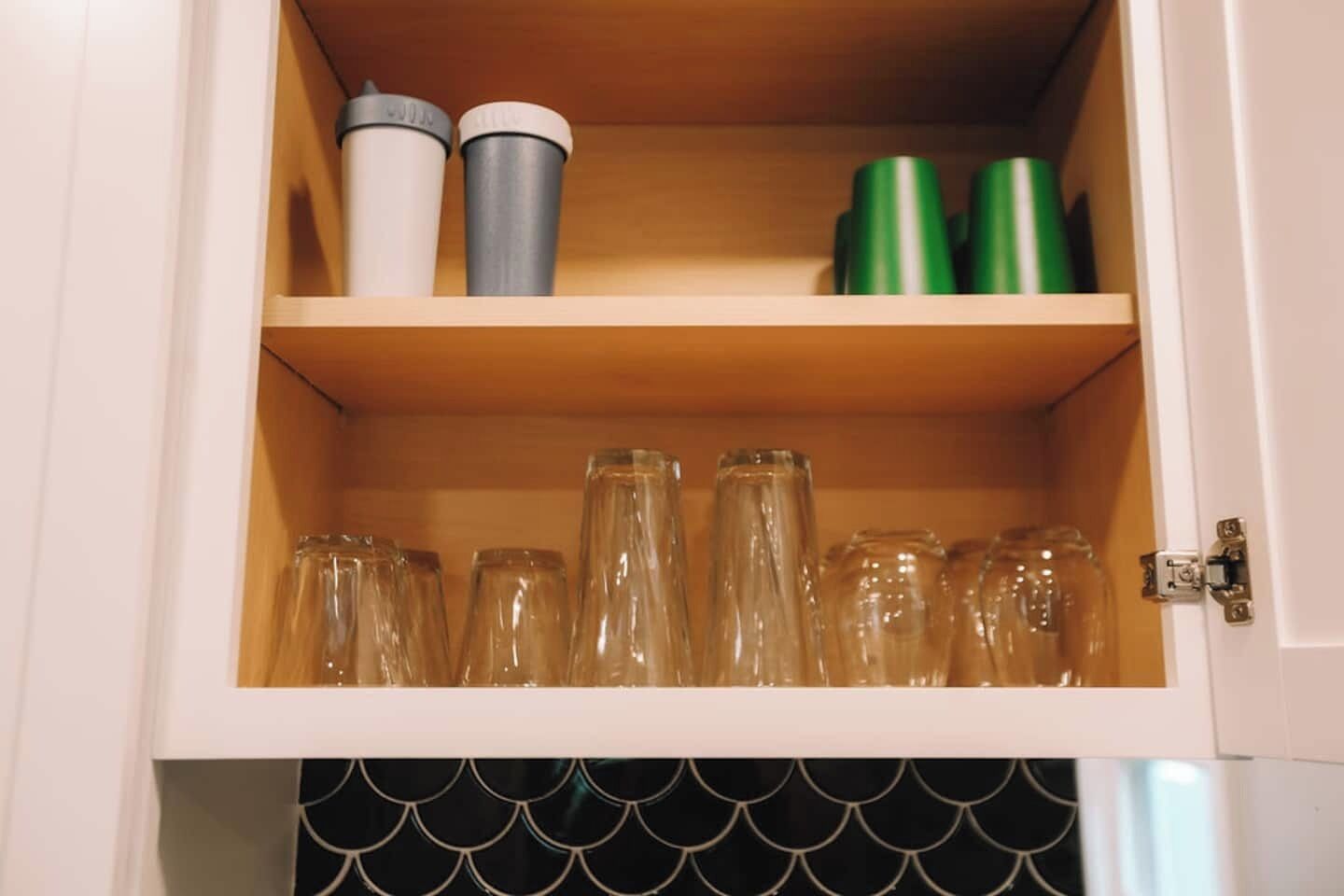 A cabinet with clear glass bottles and metal containers.