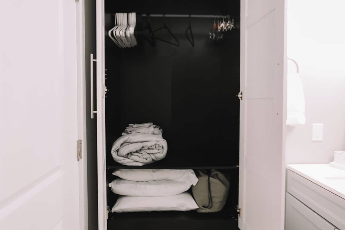 Een kast met opgevouwen kleding en een kledingroede.