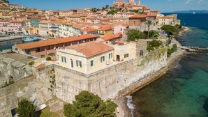 Un pueblo costero con edificios históricos, un muro fortificado y un puerto deportivo.