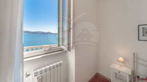 Una habitación con vista al mar, un radiador, una pequeña mesa con una lámpara y un cuadro en la pared.