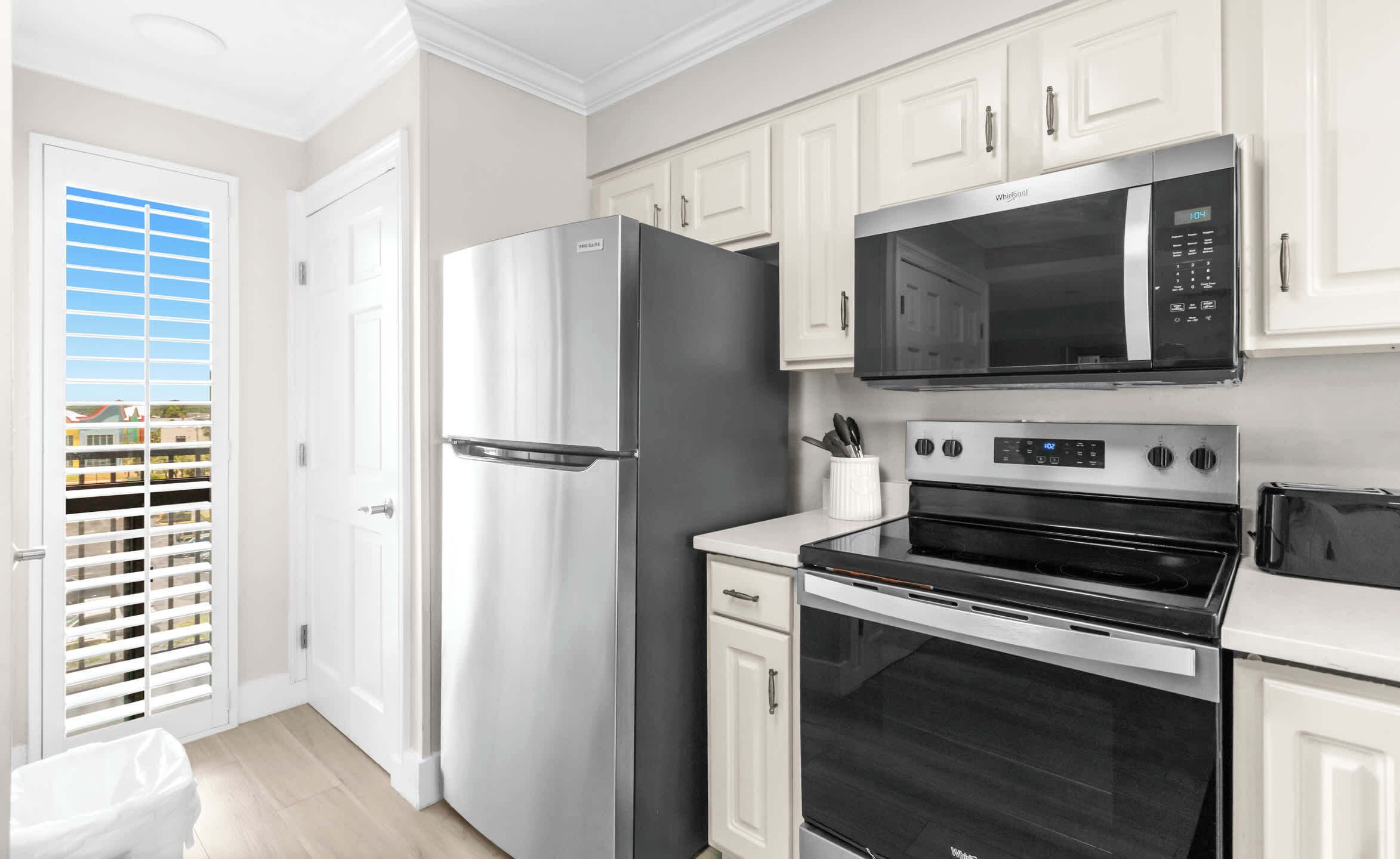 A modern kitchen with stainless steel appliances, including a refrigerator, microwave, and oven.