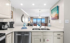 A modern kitchen with a central island, stainless steel appliances, and a view to the outside.