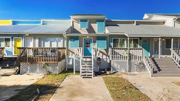 A row of beach houses with individual porches and a central entrance.