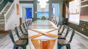 A dining area with a long table, chairs, and a view of the ocean through a glass partition.