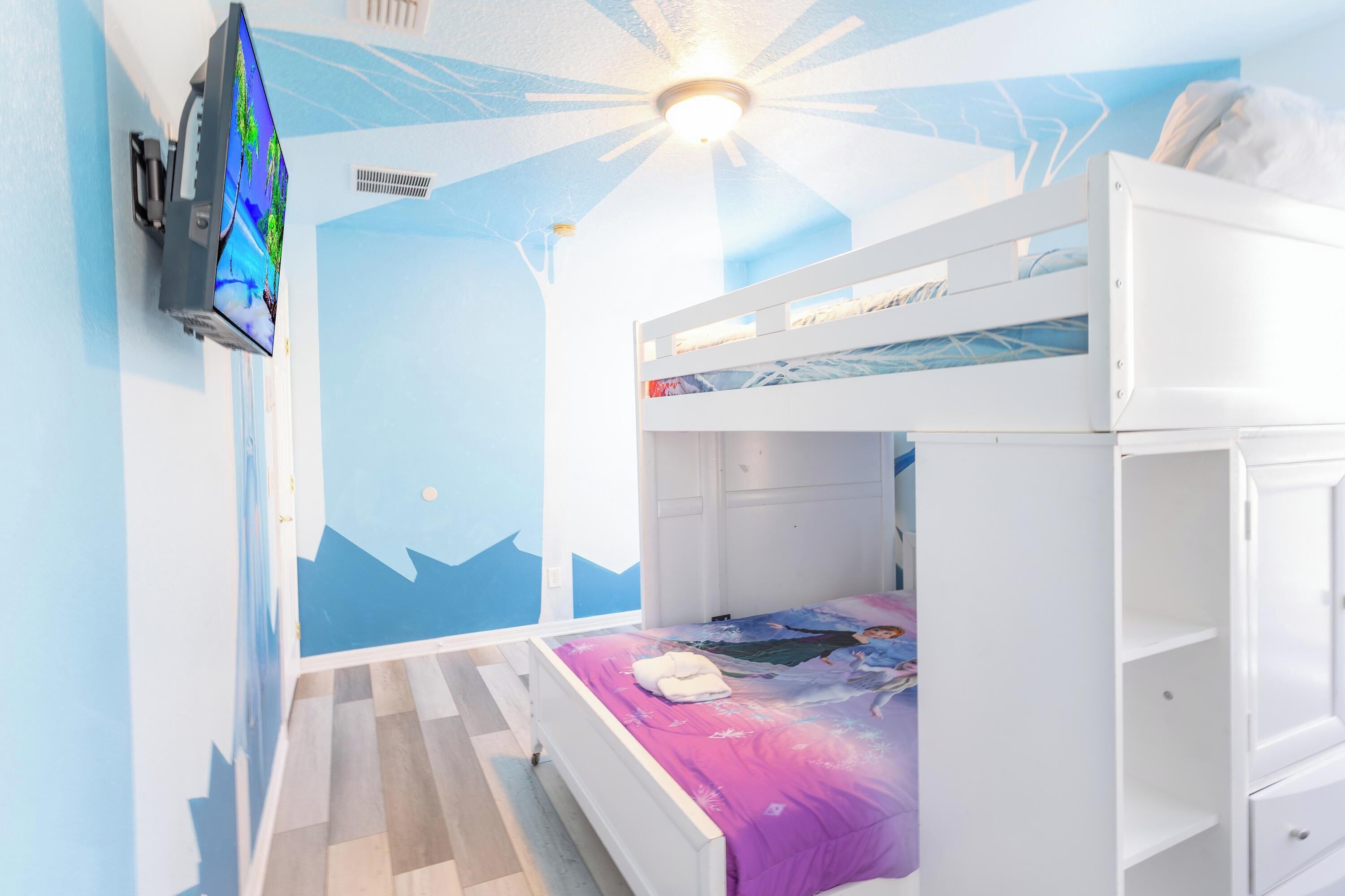 A child's bedroom with bunk beds, a TV, and a mural on the wall.