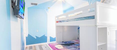 A child's bedroom with bunk beds, a TV, and a mural on the wall.