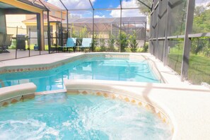 A swimming pool with a hot tub, surrounded by a covered patio area with chairs and a grill. - Awesome Movie Themed 6 Bedroom Villa, Private Pool/Spa in Gated Resort (Kissimmee)