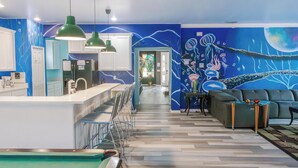 A modern kitchen with white cabinets, a central island, and a dining area with chairs.