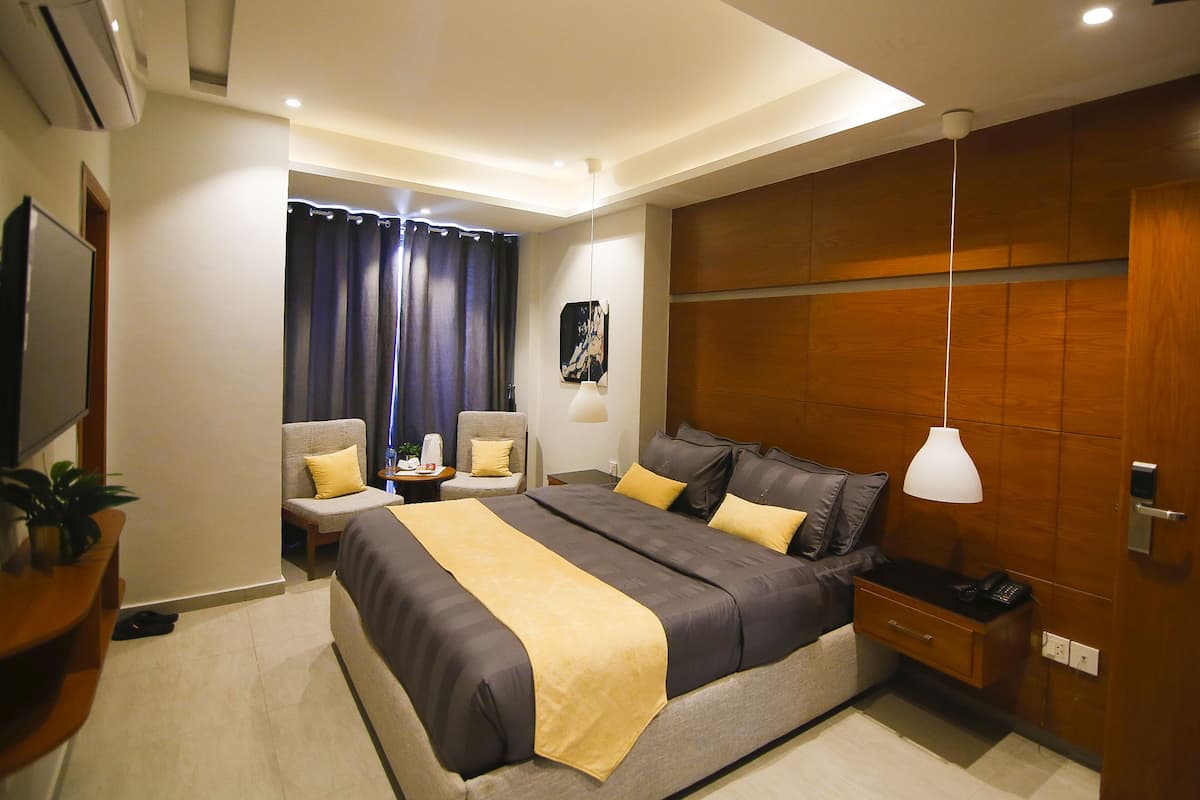 A modern bedroom with a large bed, bedside tables, a TV, and a wooden accent wall.