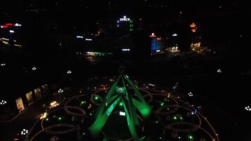 Vista nocturna de un paisaje urbano con edificios iluminados y una estructura central con luz verde.