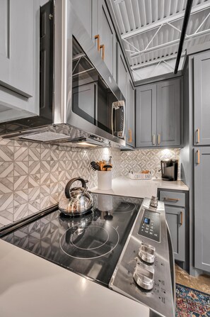 Una cocina moderna con una placa de inducción integrada, un hervidor y una cafetera sobre la encimera.