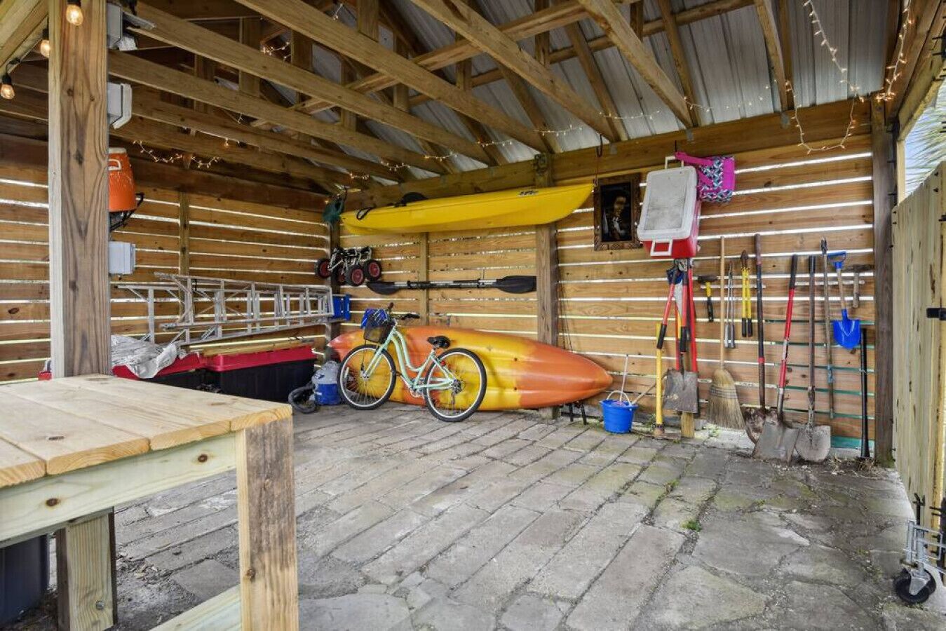 L’intérieur d’un chalet rustique, avec un kayak, un vélo et divers outils rangés sur des étagères.