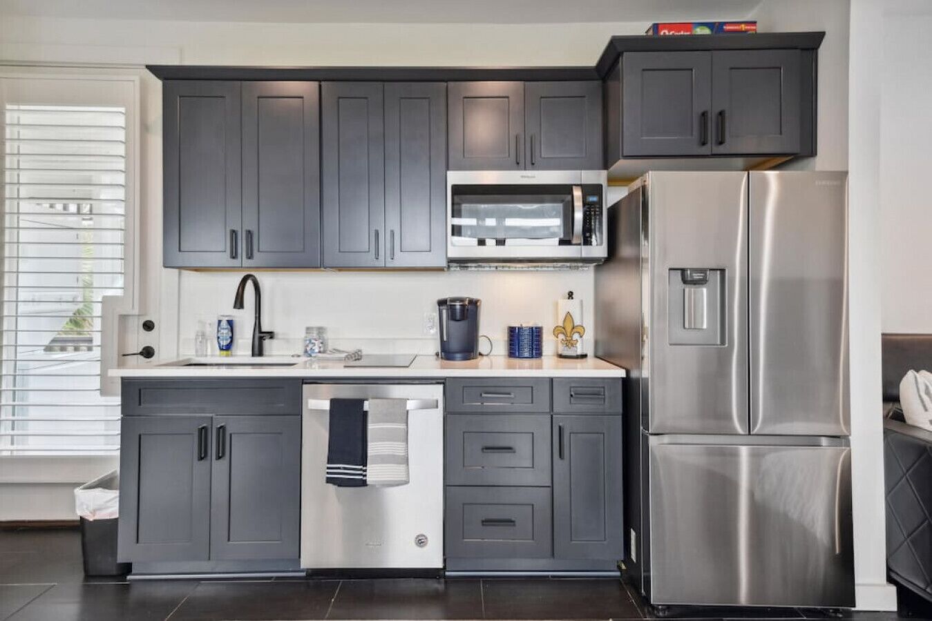 Una cocina moderna con gabinetes grises, un refrigerador de acero inoxidable, un microondas y un lavavajillas.