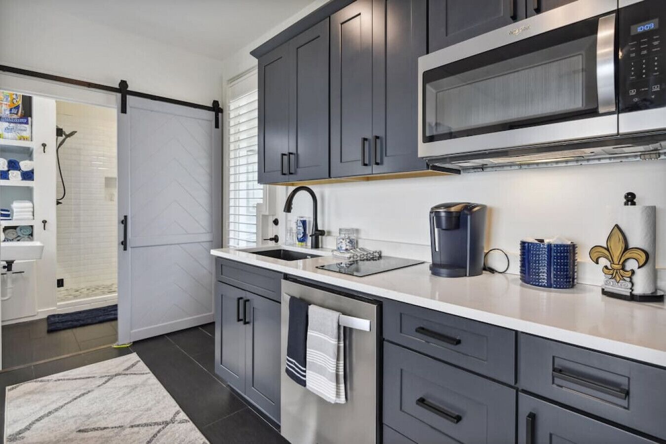 A modern kitchen with grey cabinets, a stainless steel microwave, a coffee maker, and a sink.
