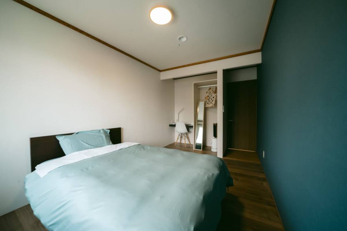 A bedroom with a bed, a desk, and a chair.