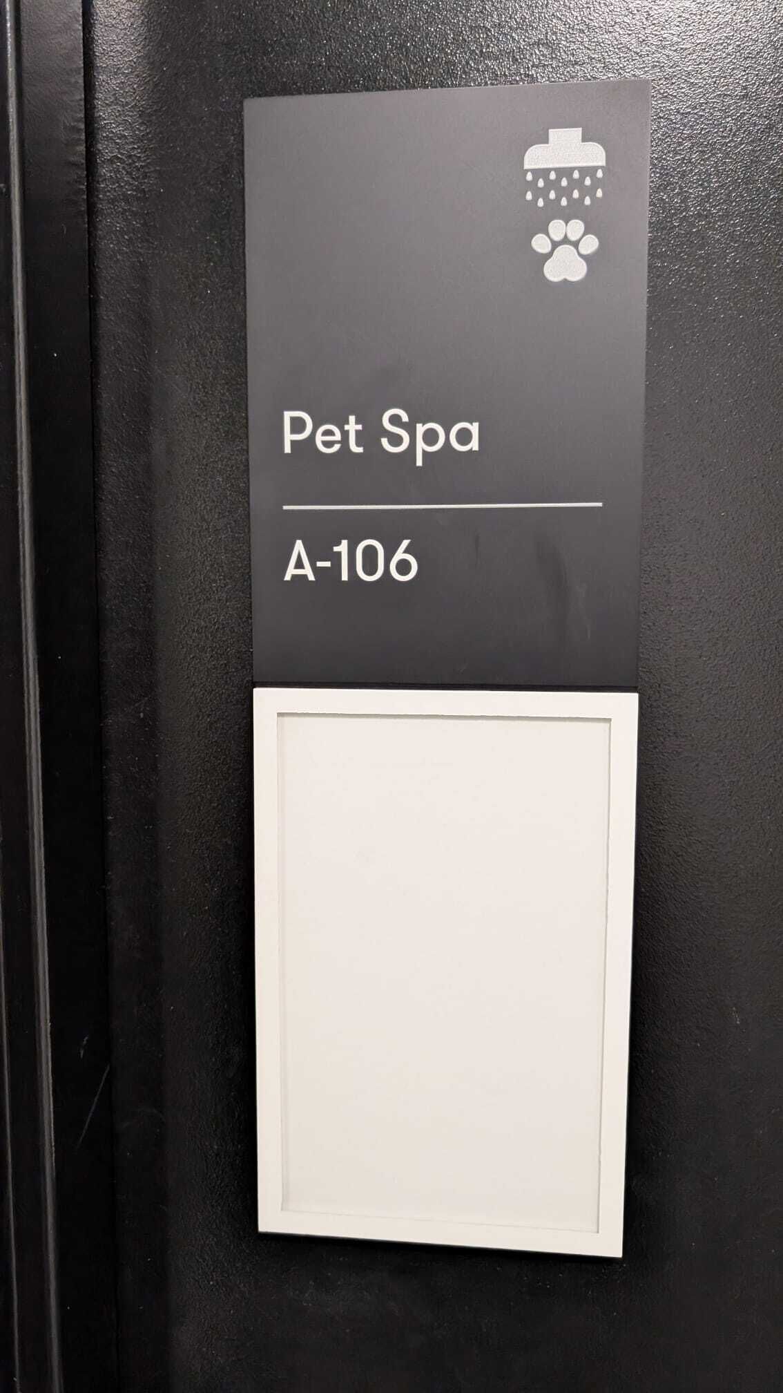 A sign for a Pet Spa labeled A-106 on a black wall.