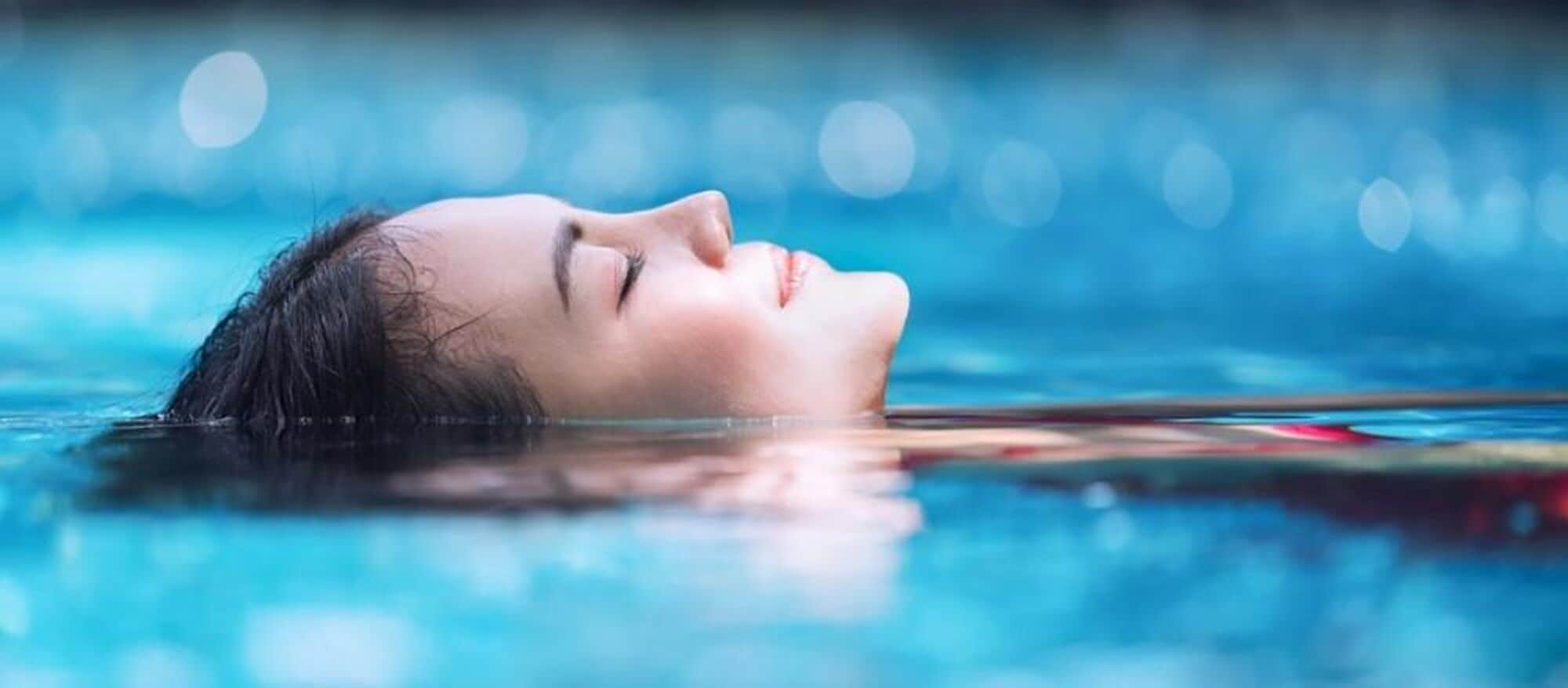 Uma pessoa deitada em uma piscina com fundo desfocado.