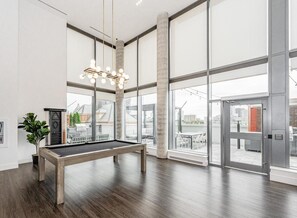 Una habitación amplia con mesa de billar, ventanas grandes y vista a la ciudad.
