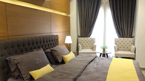 A hotel room with a large bed, two armchairs, a small table with a plant, and a window with curtains. - Space Suites (Rawalpindi)