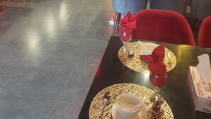 A restaurant interior with tables set for dining, red chairs, and decorative wall art. - Space Suites (Rawalpindi)