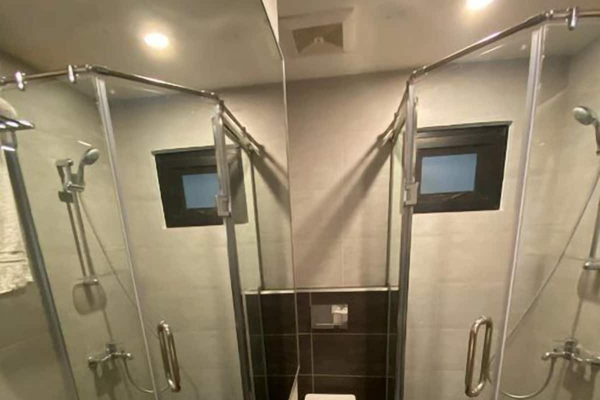 A modern bathroom with a glass-enclosed shower, a white toilet, and a large sink with a mirror.