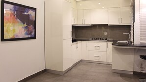 A modern kitchen with white cabinets, a black countertop, and a stainless steel sink. - Space Suites (Rawalpindi)