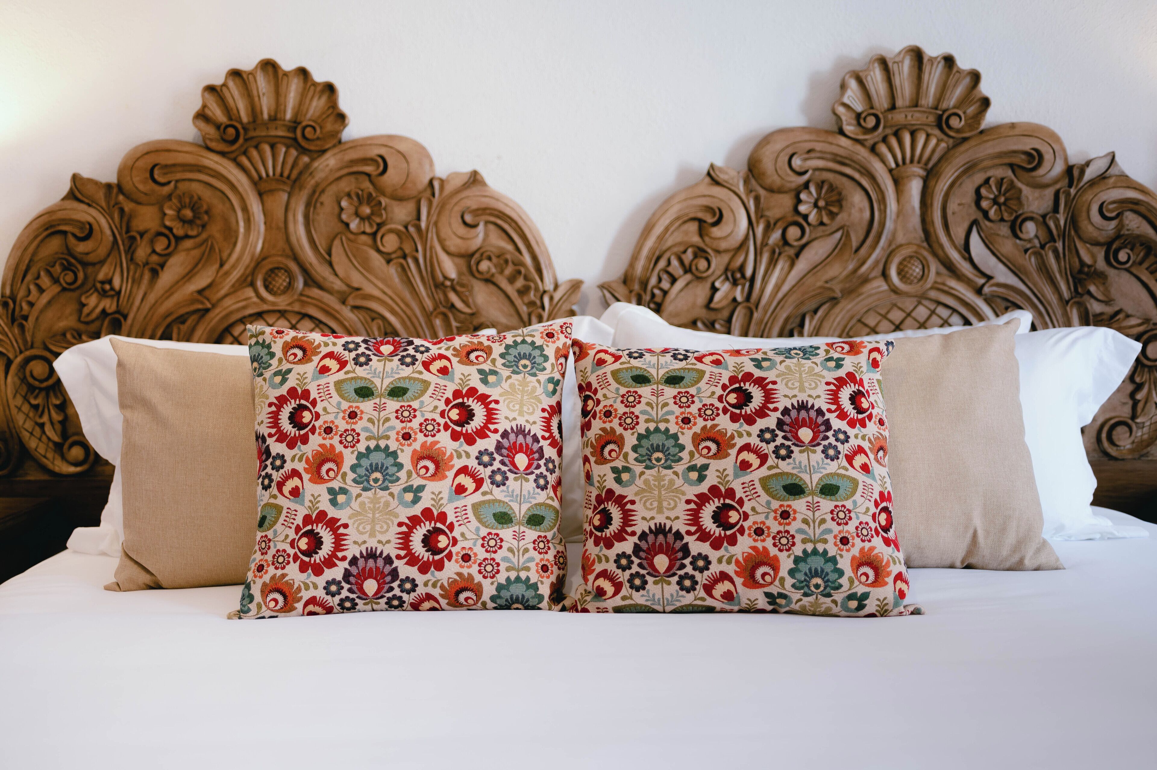 Una cama con un cabecero decorativo y dos almohadas estampadas.