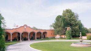 A building with a courtyard, a fountain, and a large tree.