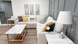 Un salon moderne avec un canapé, deux tables d’appoint et une lampe.