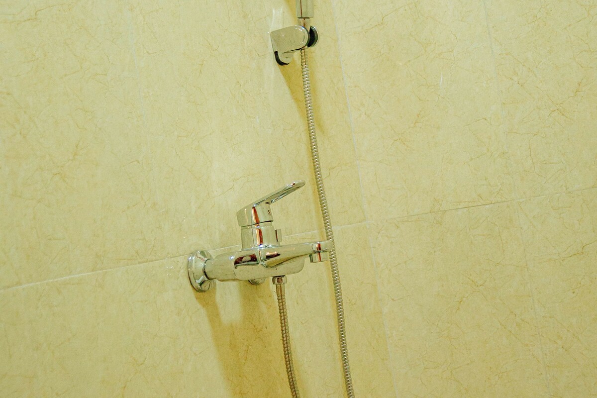 A shower with a handheld showerhead and a fixed showerhead, mounted on a tiled wall.