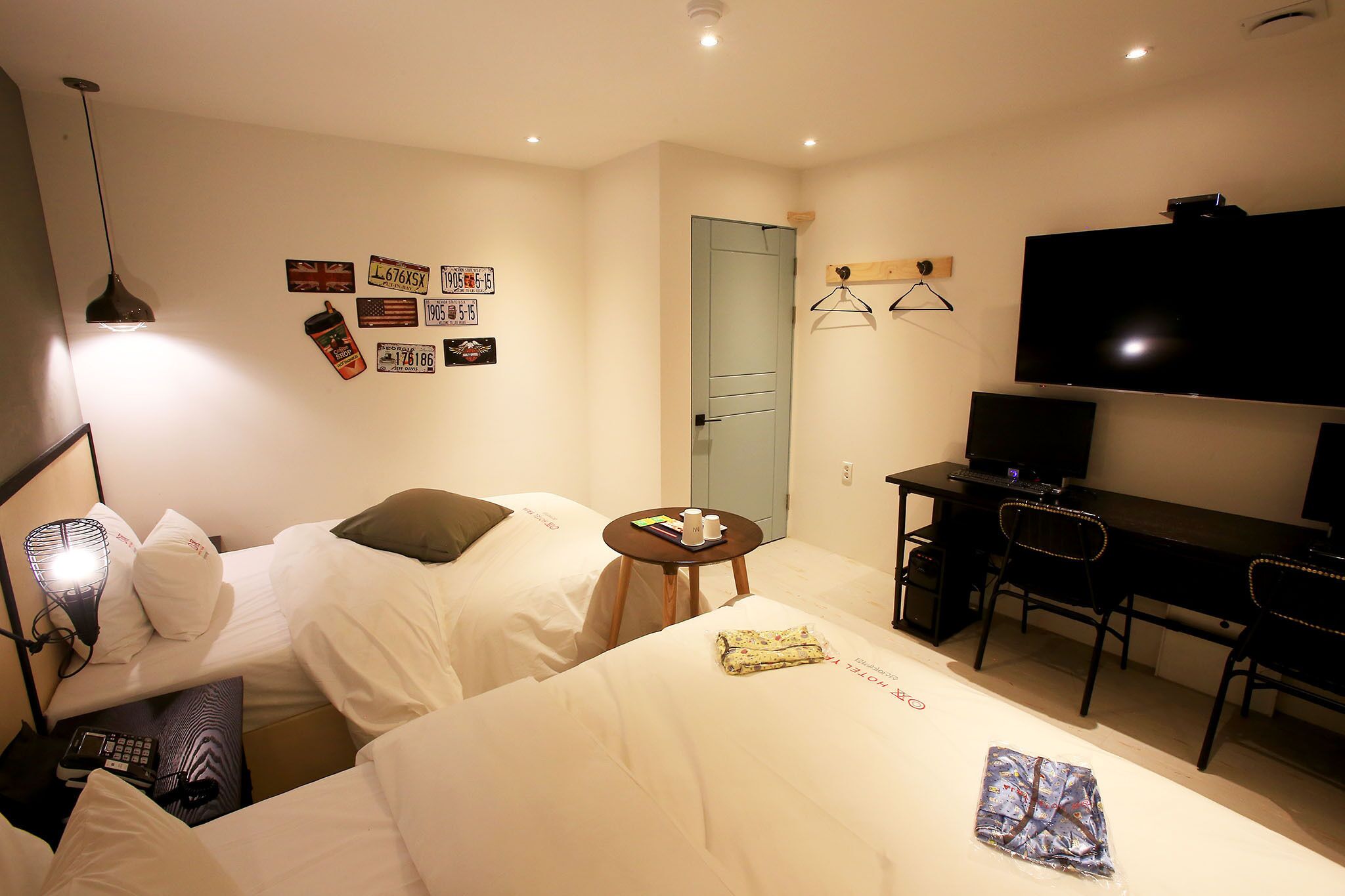 Une chambre d’hôtel avec deux lits, un bureau, une télévision et une petite table sur laquelle se trouvent une tasse et un livre.