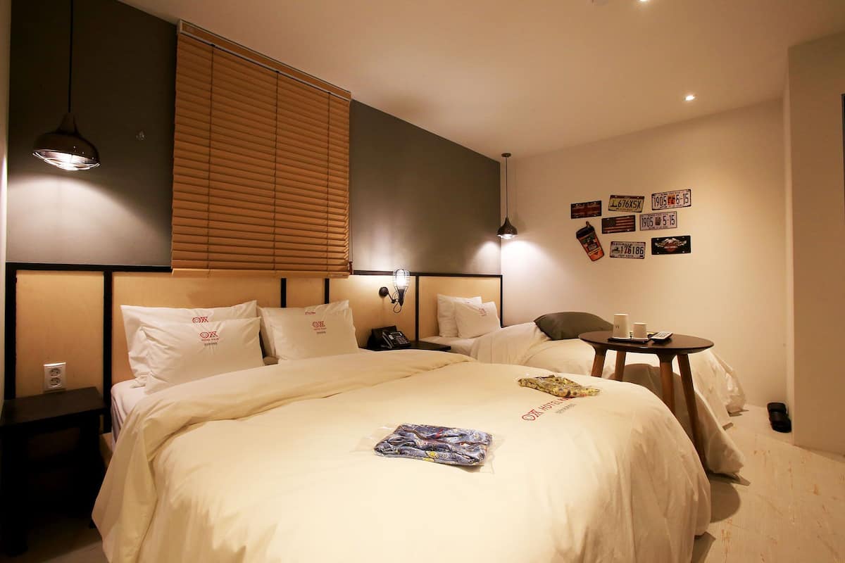 Ein Hotelzimmer mit einem großen Bett, Nachttischen, einem kleinen Schreibtisch und einem am Wand montierten Fernseher.