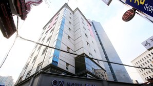 Un grand immeuble d’hôtel, avec une enseigne indiquant « HÔTEL YAJA » à sa base.