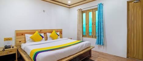 A neatly arranged bedroom with a wooden bed, a nightstand, a window with curtains, and a wooden door.