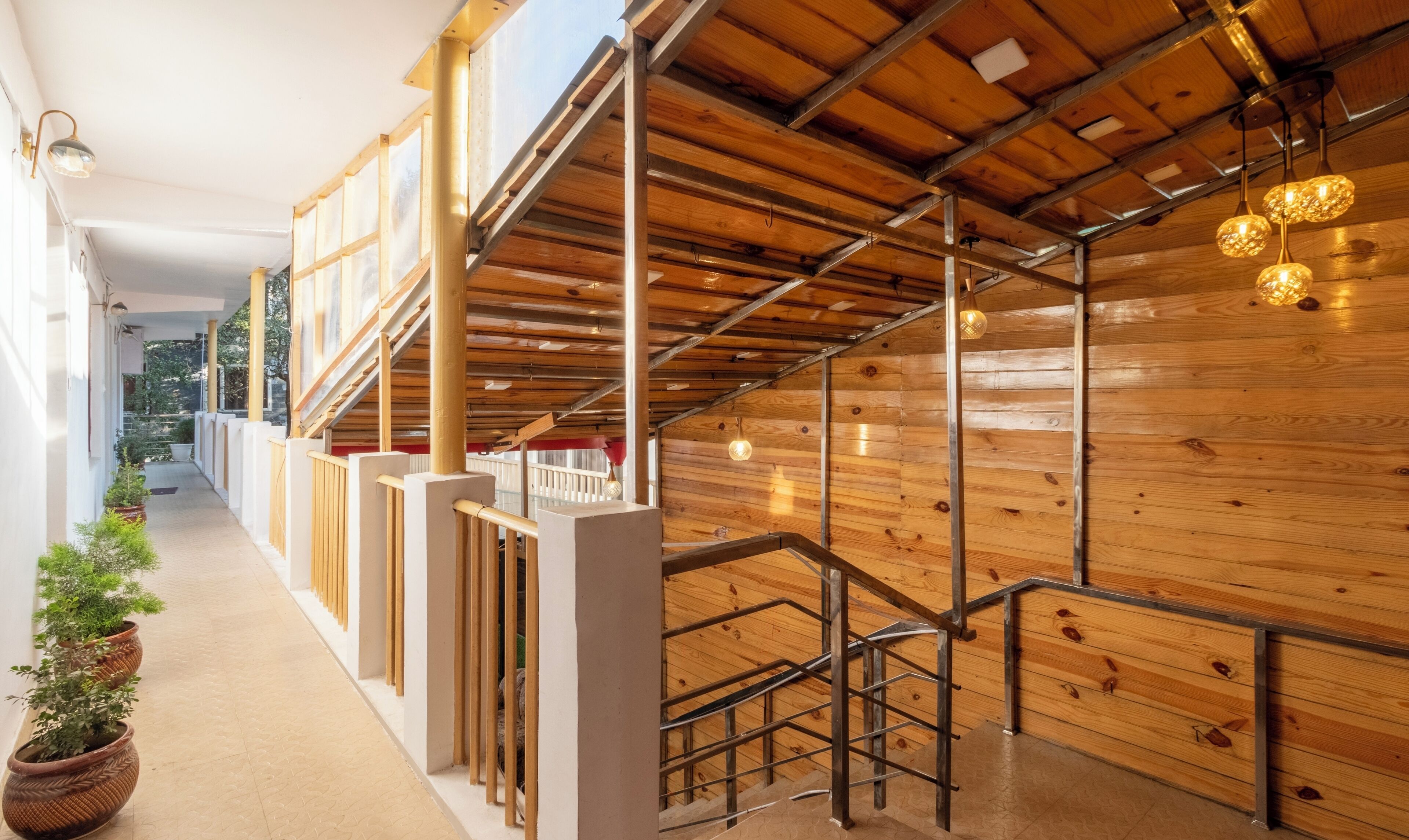 A modern interior with wooden panel walls, a staircase with metal railings, and a corridor with potted plants.