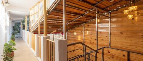 A modern interior with wooden panel walls, a staircase with metal railings, and a corridor with potted plants.