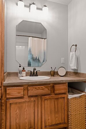 A bathroom with a wooden vanity, a large mirror, and a sink.