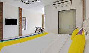 Habitación de hotel con una cama grande, un televisor de pantalla plana montado en la pared, una ventana con cortinas y una pared de acento de madera.
