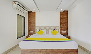 Un dormitorio moderno con cama, cabecera de madera y pared blanca.