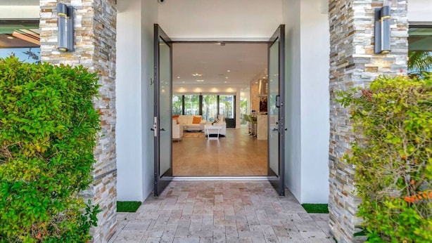 A modern building entrance with a glass door leading to a well-lit interior. - Lynora`s Luxe Estate - 3BR/3BA w/ Modern Design & Heated Pool (Fort Lauderdale)