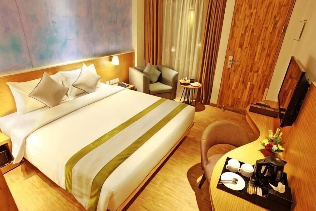 Une chambre d’hôtel avec un grand lit, un bureau avec une chaise, une petite table et un téléviseur.