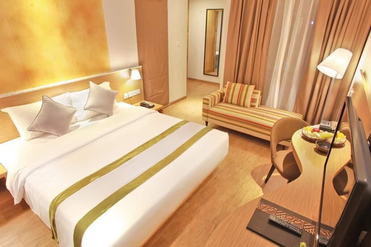 Une chambre d’hôtel avec un grand lit, un canapé, une petite table avec des fruits et une télévision.