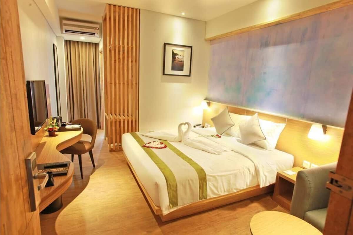 Une chambre d’hôtel avec un lit, un bureau, une chaise et un grand tableau au mur.