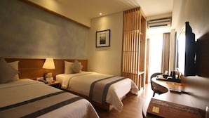 A hotel room with two beds, a desk, a chair, a TV, and a window with curtains. - Liberta Hotel Jimbaran (Kedonganan)