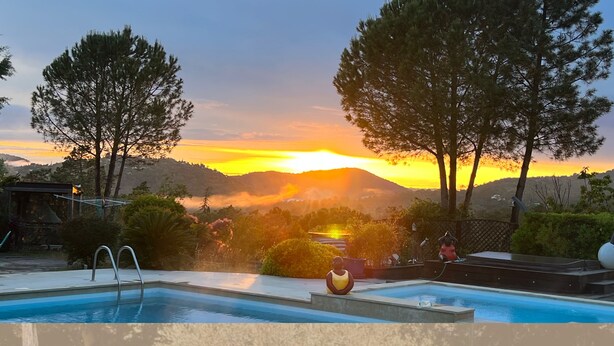 Une piscine offrant une vue sur le coucher de soleil et les montagnes en arrière-plan.